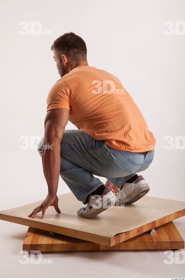 Kneeling pose orange thsirt light blue jeans of bodybuilder Harold