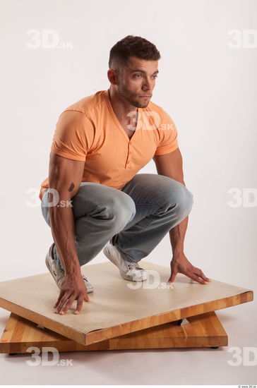 Kneeling pose orange thsirt light blue jeans of bodybuilder Harold