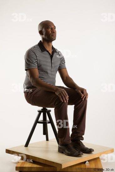 Sitting reference of whole body black white striped shirt brown jeans brown shoes Arturo