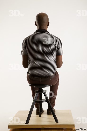 Sitting reference of whole body black white striped shirt brown jeans brown shoes Arturo